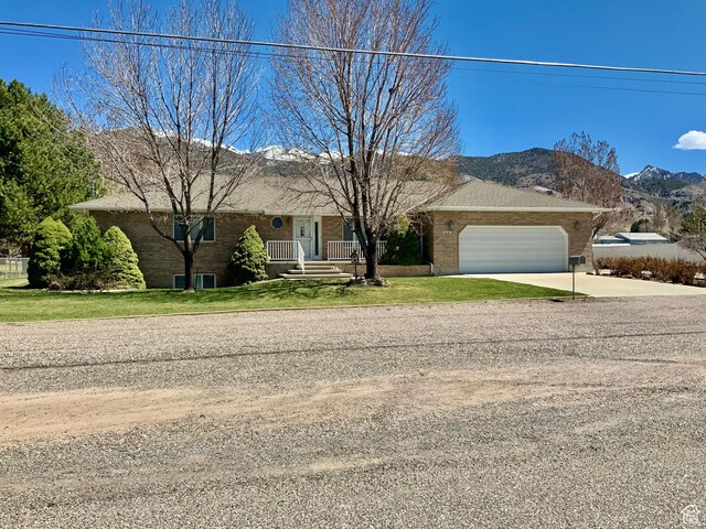 ranch-style house with a garage, a mountain view, and a front lawn