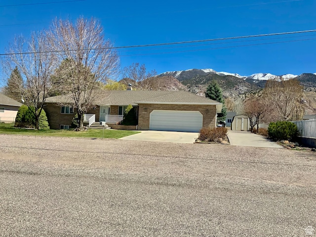 ranch-style house with a storage unit, a mountain view, and a garage