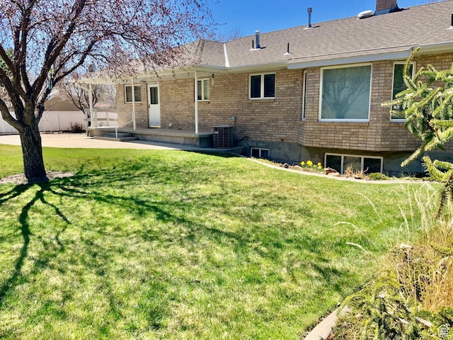rear view of property with central AC, a patio, and a lawn