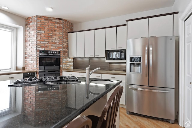 5845 Kerry Cir, Murray, UT 84107 - kitchen with light hardwood / wood-style flooring, white cabinets, black appliances, sink, and dark stone countertops