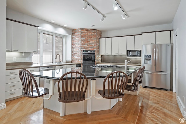 5845 Kerry Cir, Murray, UT 84107 - kitchen with a kitchen breakfast bar, black appliances, white cabinets, and a center island