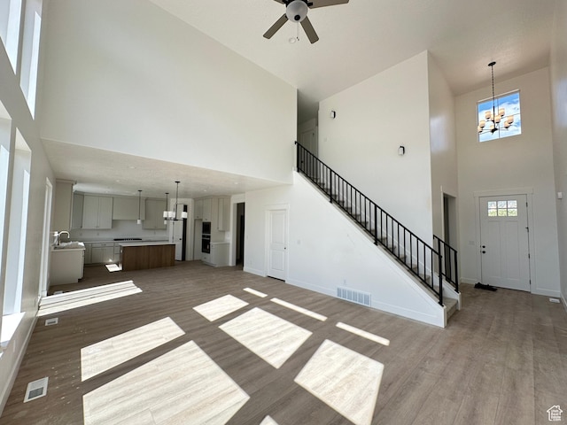 325 N 1040 E Unit 26, Salem, UT 84653 - unfurnished living room featuring a towering ceiling, wood finished floors, ceiling fan, stairway, and a chandelier