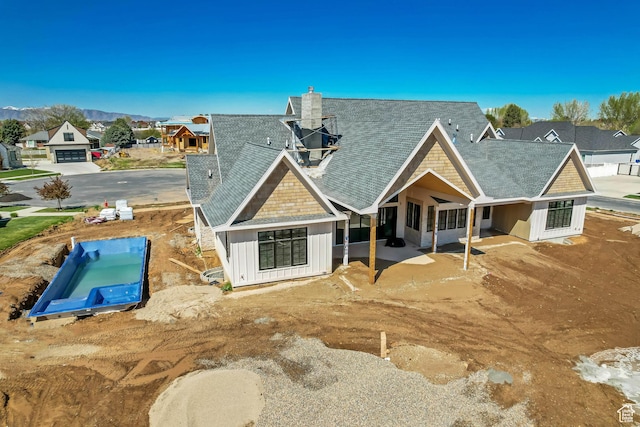 rear view of house with board and batten siding, a residential view, and roof with shingles