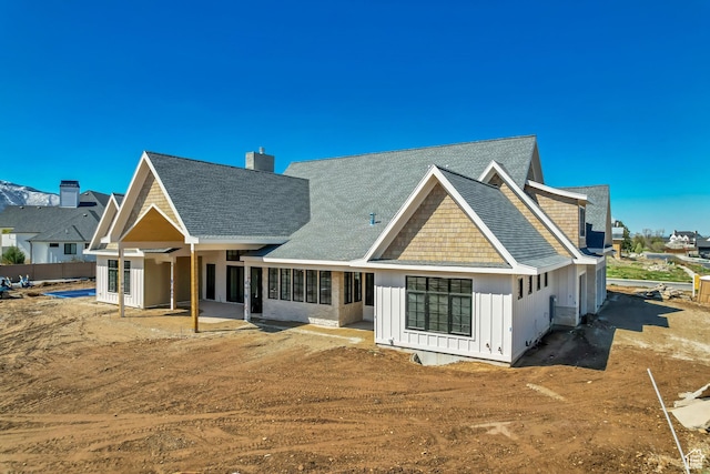 back of property featuring a shingled roof, board and batten siding, and a chimney