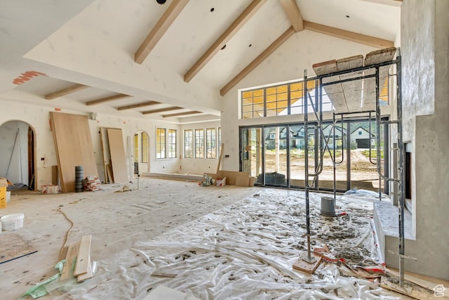 unfurnished living room with arched walkways, high vaulted ceiling, and beam ceiling