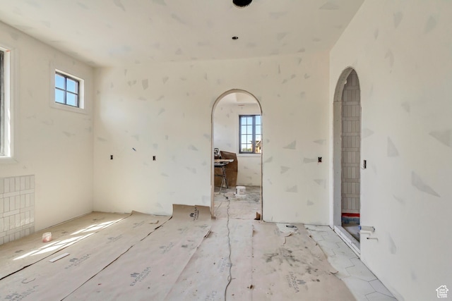 empty room with a healthy amount of sunlight and arched walkways
