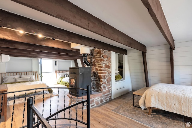 10481 E Spring Creek Dr Unit 722, Heber City, UT 84032 - bedroom with an AC wall unit, beamed ceiling, wood walls, light hardwood / wood-style floors, and a wood stove