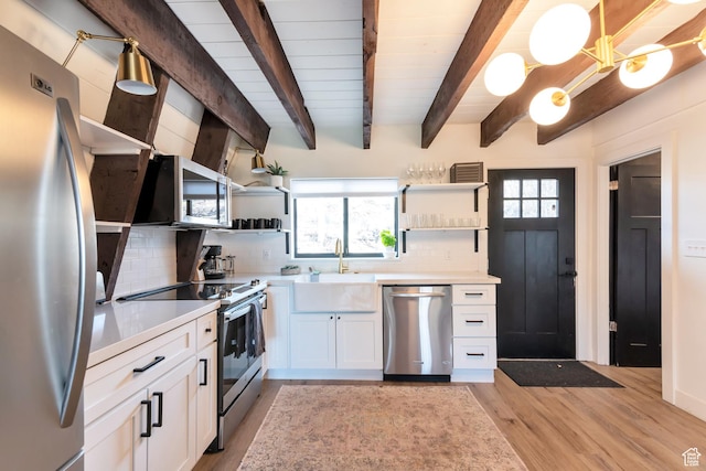 kitchen featuring white cabinetry, beam ceiling, decorative light fixtures, tasteful backsplash, and appliances with stainless steel finishes