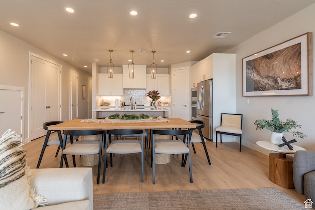 5398 S Aquamarine Ln, St George, UT 84790 - kitchen featuring white cabinetry, light wood-type flooring, stainless steel appliances, decorative light fixtures, and tasteful backsplash