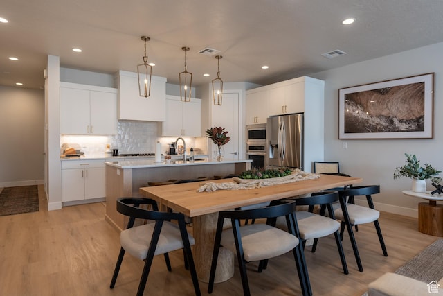 5398 S Aquamarine Ln, St George, UT 84790 - kitchen featuring a center island with sink, stainless steel appliances, white cabinets, decorative light fixtures, and backsplash