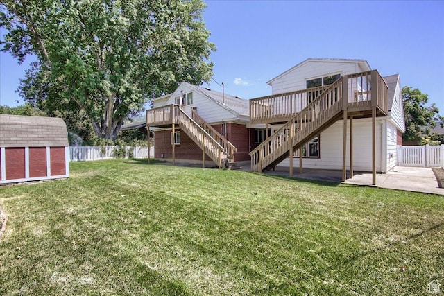 back of property with a storage unit, a deck, a yard, and a patio area