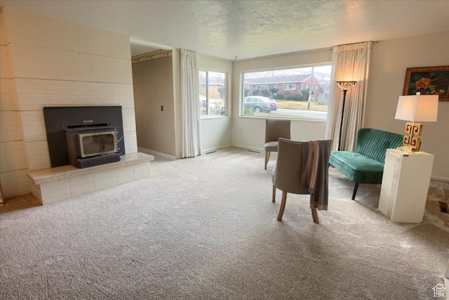 living area with a textured ceiling, a wood stove, and light colored carpet