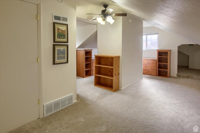 additional living space with a textured ceiling, light carpet, vaulted ceiling, and ceiling fan
