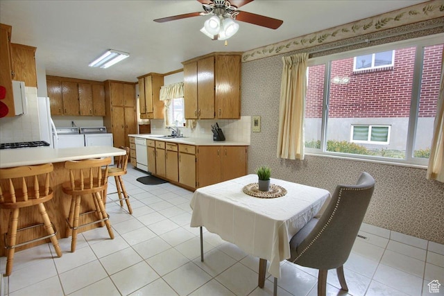 kitchen with white dishwasher, tasteful backsplash, washer and clothes dryer, light tile patterned floors, and sink