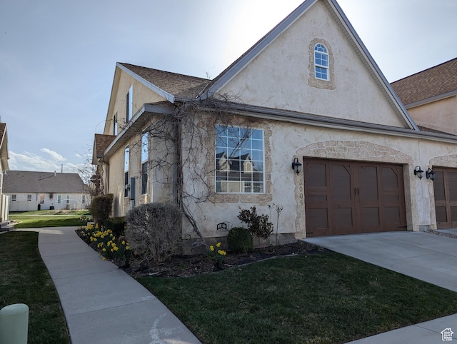 view of side of property with concrete driveway, stucco siding, and a lawn