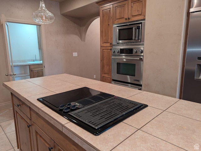 3006 E Somerset Dr, Spanish Fork, UT 84660 - kitchen with tile countertops, arched walkways, appliances with stainless steel finishes, a sink, and brown cabinets