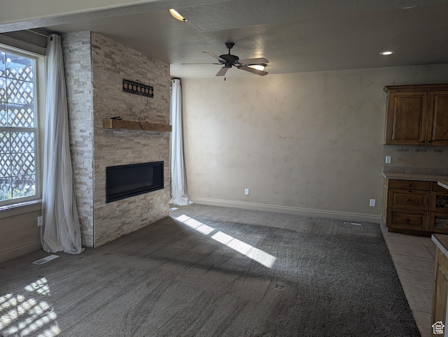 3006 E Somerset Dr, Spanish Fork, UT 84660 - unfurnished living room featuring visible vents, baseboards, a stone fireplace, a ceiling fan, and light colored carpet