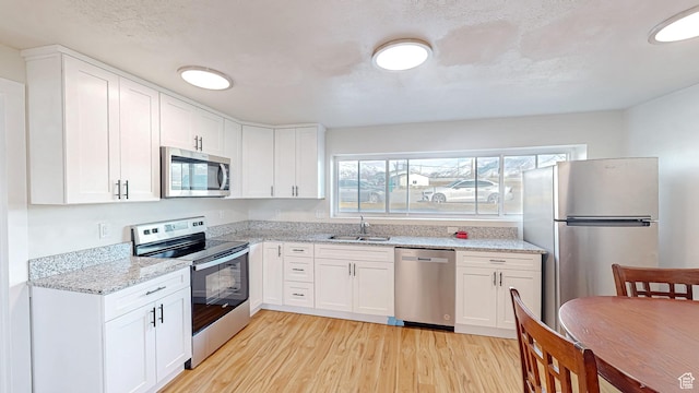 1125 N Trinnaman Ln, Lehi, UT 84043 - kitchen with white cabinetry, light hardwood / wood-style floors, sink, light stone counters, and appliances with stainless steel finishes