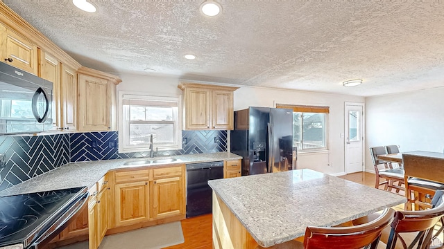 1125 N Trinnaman Ln, Lehi, UT 84043 - kitchen with light hardwood / wood-style flooring, sink, a kitchen island, black appliances, and decorative backsplash