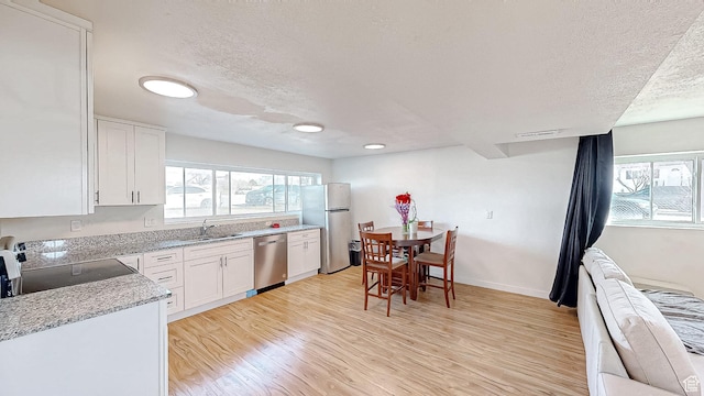 1125 N Trinnaman Ln, Lehi, UT 84043 - kitchen with a textured ceiling, white cabinetry, stainless steel appliances, and light hardwood / wood-style flooring