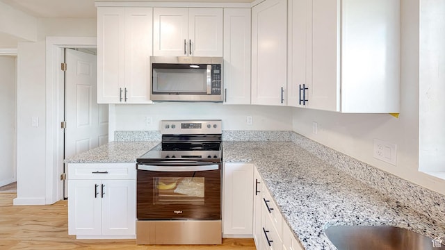 1125 N Trinnaman Ln, Lehi, UT 84043 - kitchen featuring appliances with stainless steel finishes, light hardwood / wood-style floors, light stone countertops, and white cabinets