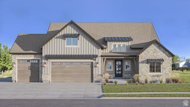 view of front of property with stone siding, board and batten siding, an attached garage, and driveway