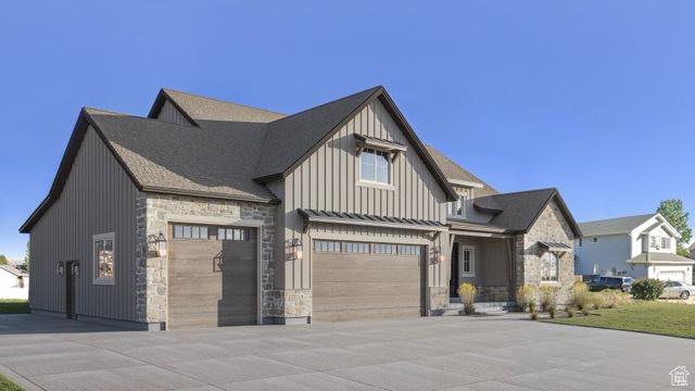 view of front of property with board and batten siding, stone siding, an attached garage, and concrete driveway