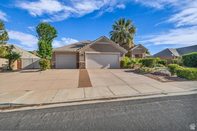 699 E Lost Dr, Washington, UT 84780 - view of front of house with stucco siding, a tiled roof, a garage, stone siding, and concrete driveway