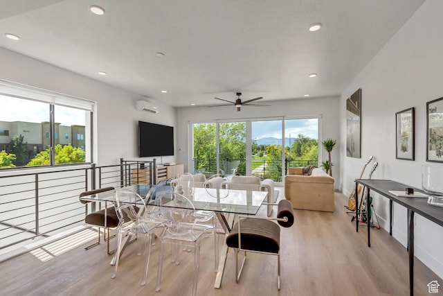dining area with ceiling fan, an AC wall unit, a wealth of natural light, and light wood-style floors