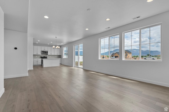 1972 S 2475 W, West Haven, UT 84401 - unfurnished living room with a chandelier, recessed lighting, a mountain view, baseboards, and light wood-style flooring