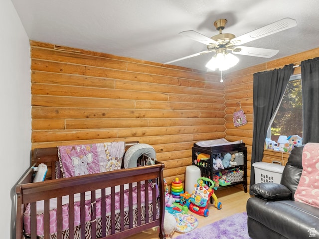 bedroom featuring wood finished floors, log walls, and a ceiling fan