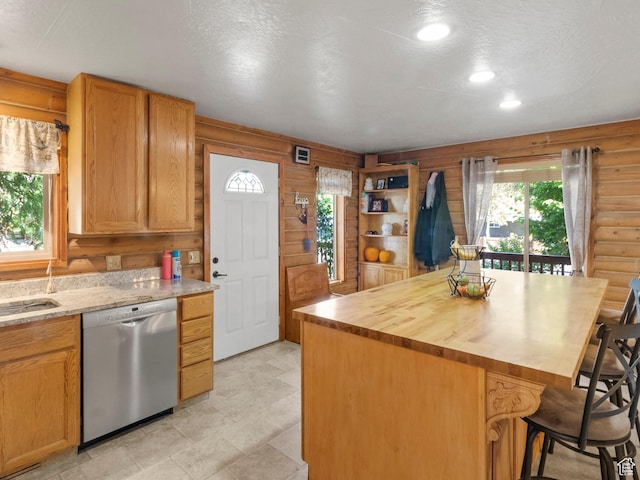 kitchen with a textured ceiling, log walls, a center island, dishwasher, and a kitchen bar