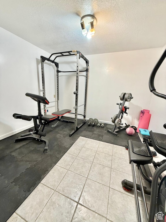 exercise room with a textured ceiling and baseboards