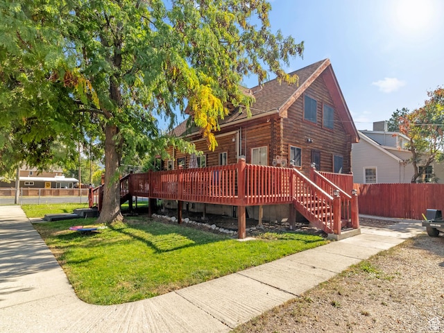 view of front of house with a deck, fence, stairway, log exterior, and a front yard