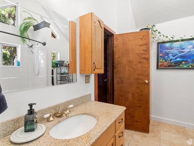 full bathroom featuring baseboards, a tile shower, vanity, and tile patterned floors