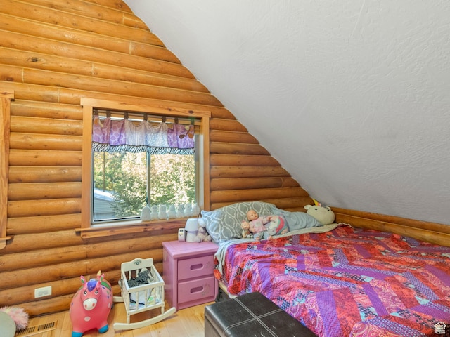 bedroom featuring visible vents, log walls, and wood finished floors