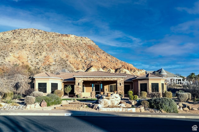 exterior space featuring a mountain view, a tile roof, stone siding, and stucco siding