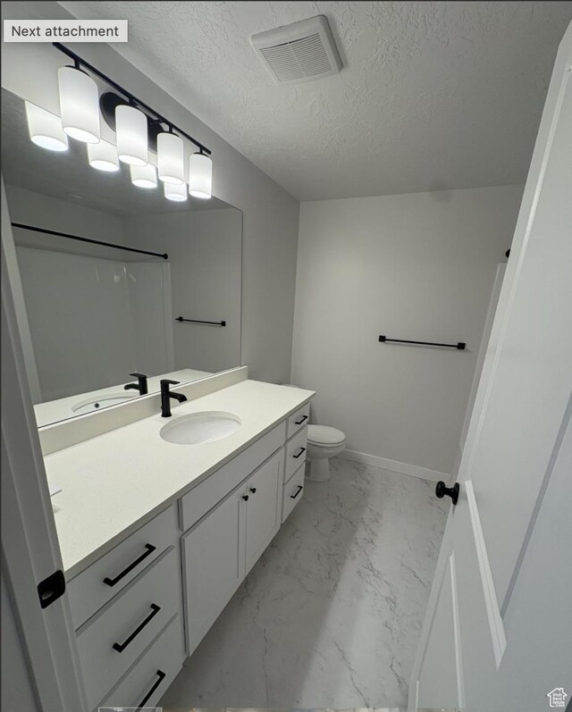 bathroom featuring toilet, vanity, a textured ceiling, and a shower