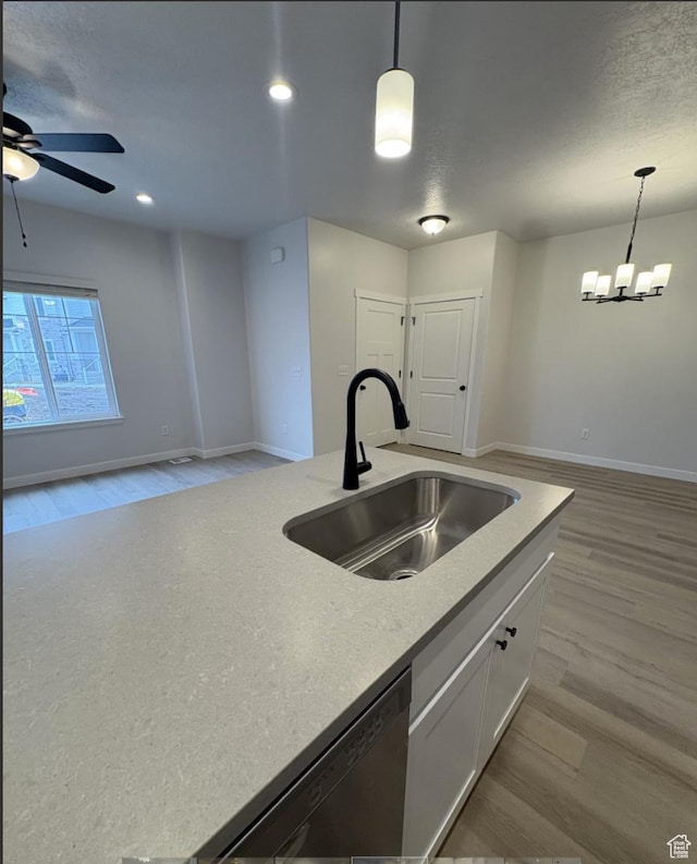 kitchen with dishwasher, sink, pendant lighting, and white cabinets