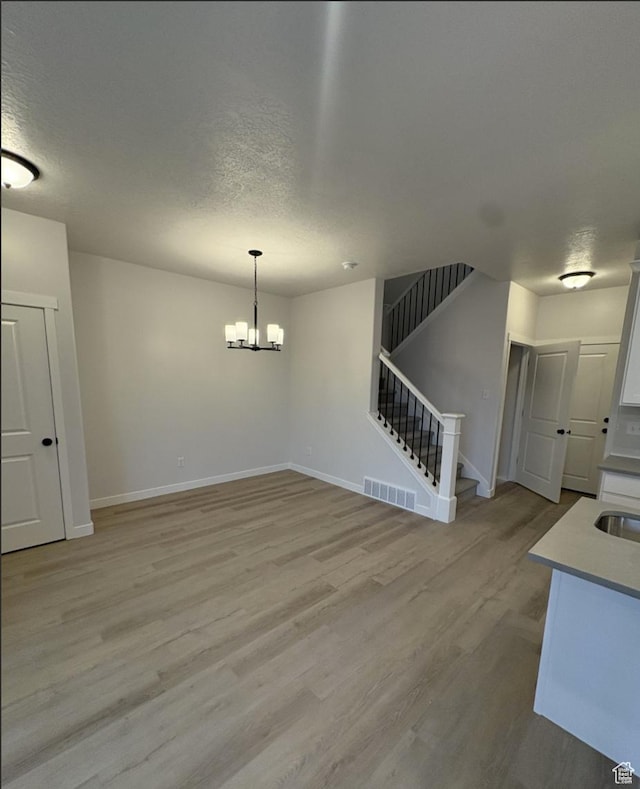 interior space with light hardwood / wood-style flooring, a chandelier, and a textured ceiling