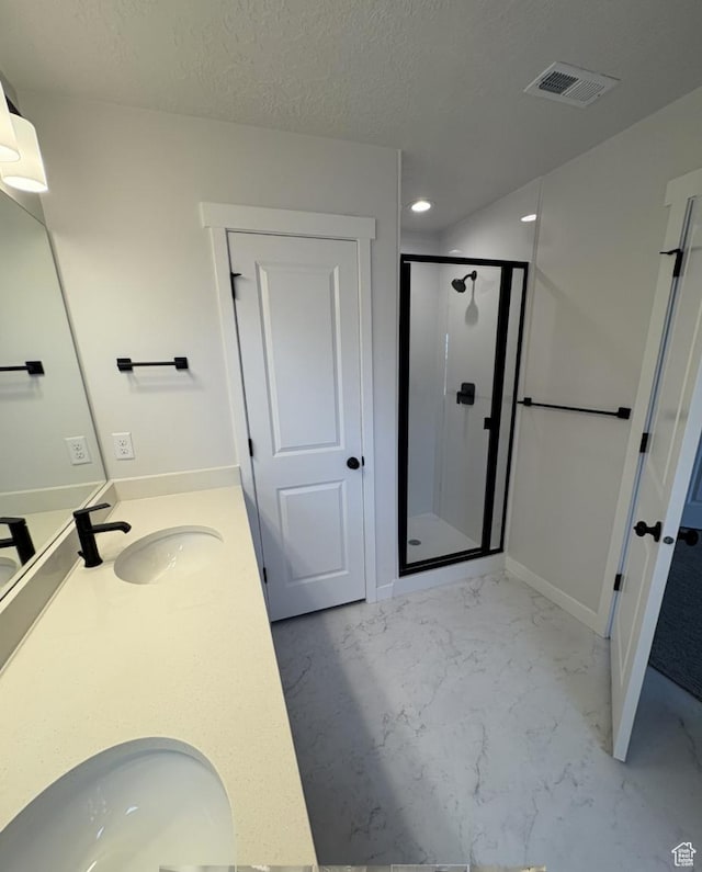 bathroom with a textured ceiling, a shower with shower door, and vanity