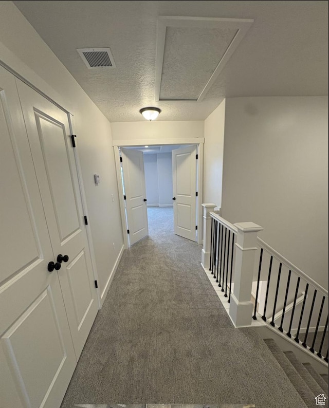 hall featuring carpet and a textured ceiling