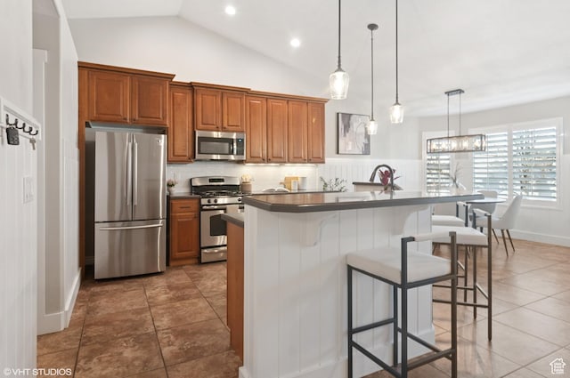 672 W 1900 S, Syracuse, UT 84075 - kitchen with brown cabinets, dark countertops, appliances with stainless steel finishes, and a breakfast bar