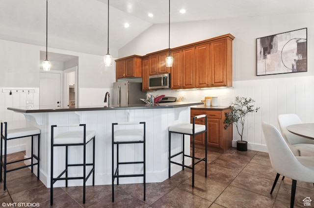 672 W 1900 S, Syracuse, UT 84075 - kitchen featuring a kitchen breakfast bar, dark countertops, appliances with stainless steel finishes, brown cabinetry, and lofted ceiling