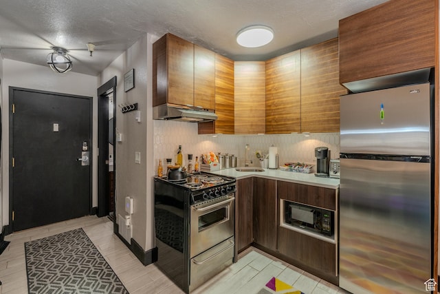 kitchen with stainless steel appliances, tasteful backsplash, a textured ceiling, and sink