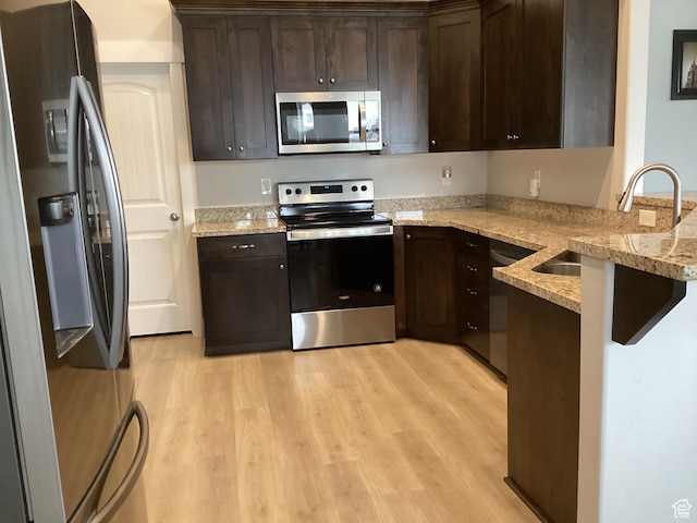 263 E Somerest Ln N, Stansbury Park, UT 84074 - kitchen featuring appliances with stainless steel finishes, dark brown cabinets, light stone countertops, sink, and kitchen peninsula