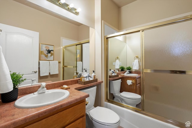 full bathroom featuring toilet, combined bath / shower with glass door, and vanity
