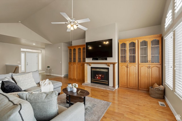 living room with a fireplace, plenty of natural light, light wood-type flooring, and high vaulted ceiling