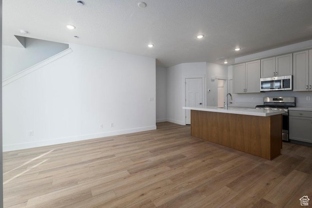 1773 W 160 S Unit 43, Pleasant Grove, UT 84062 - kitchen with an island with sink, appliances with stainless steel finishes, light wood-style floors, and gray cabinetry