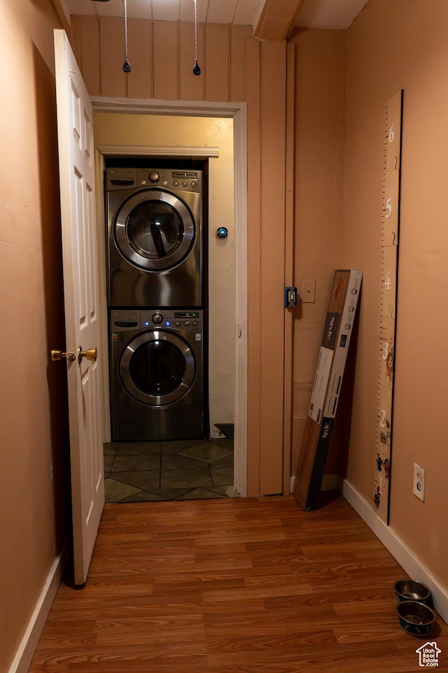 clothes washing area featuring stacked washer and clothes dryer and light hardwood / wood-style flooring